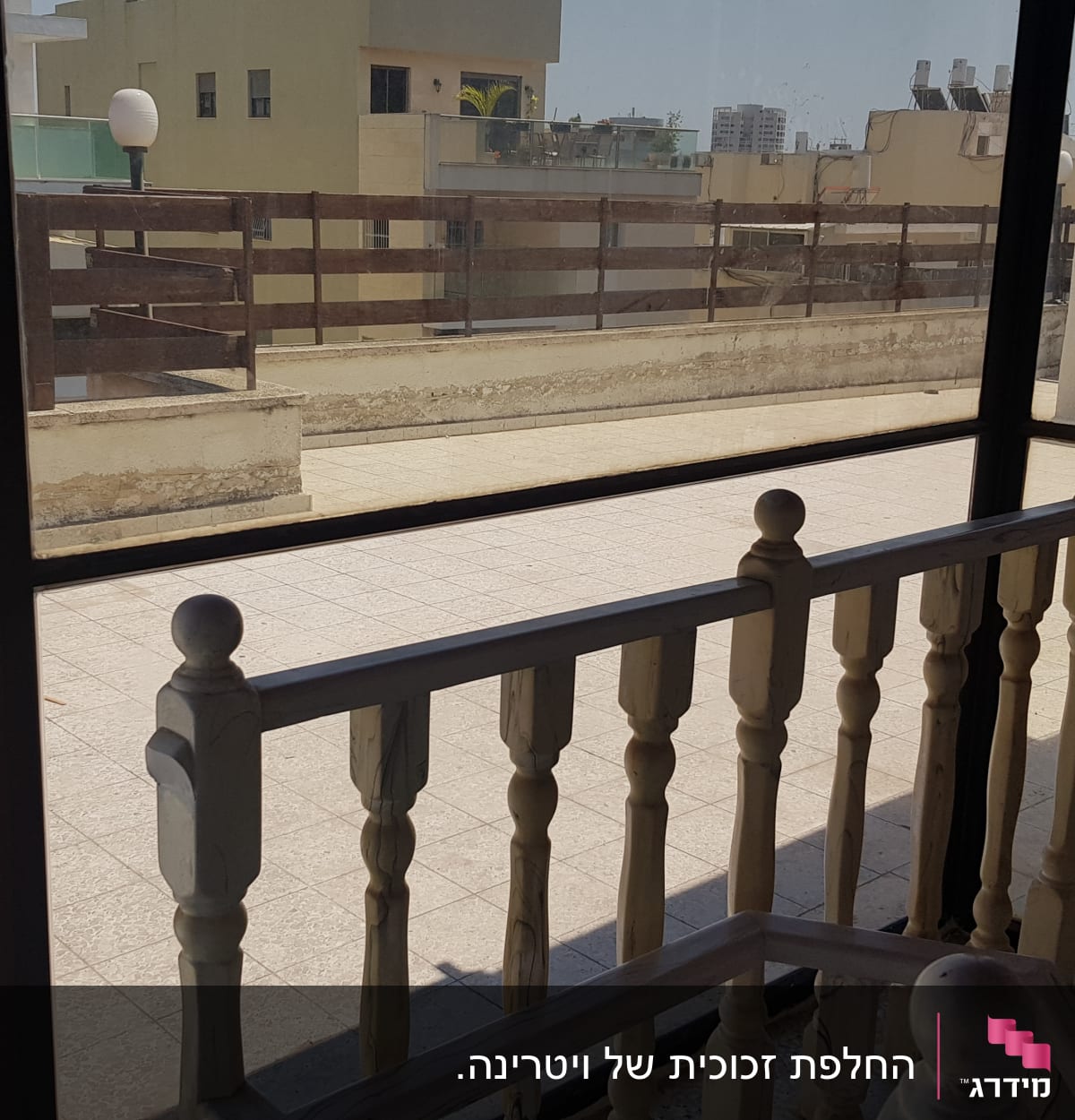 חלון זכוכית גדול עם נוף למרפסת וגדר עץ